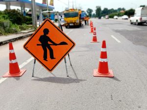 Road construction sign with cones and work truck on road